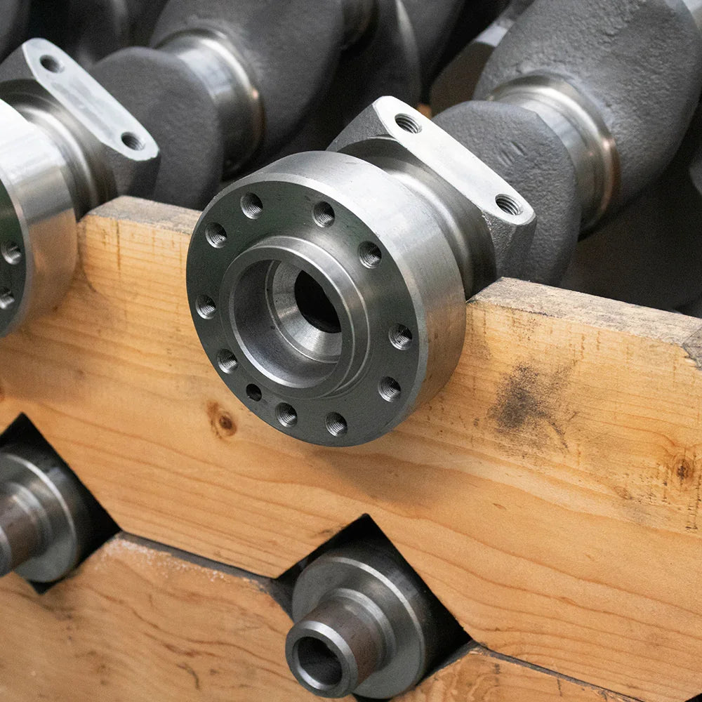 Close-up of a metal industrial flange mounted on a textured wooden board with multiple machined holes