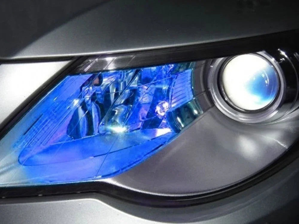 Close-up of modern car headlight with blue tinted reflector and projector lens on silver vehicle