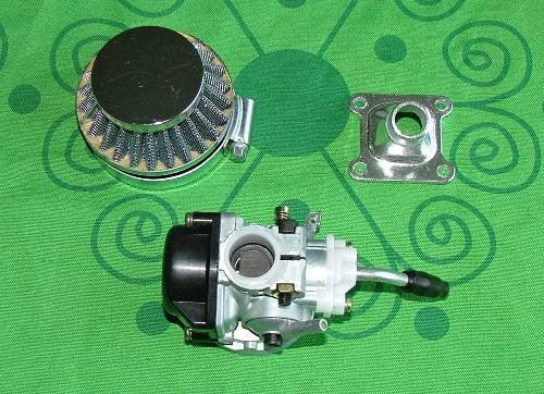 Motorcycle carburetor with air filter and mounting flange on green patterned fabric