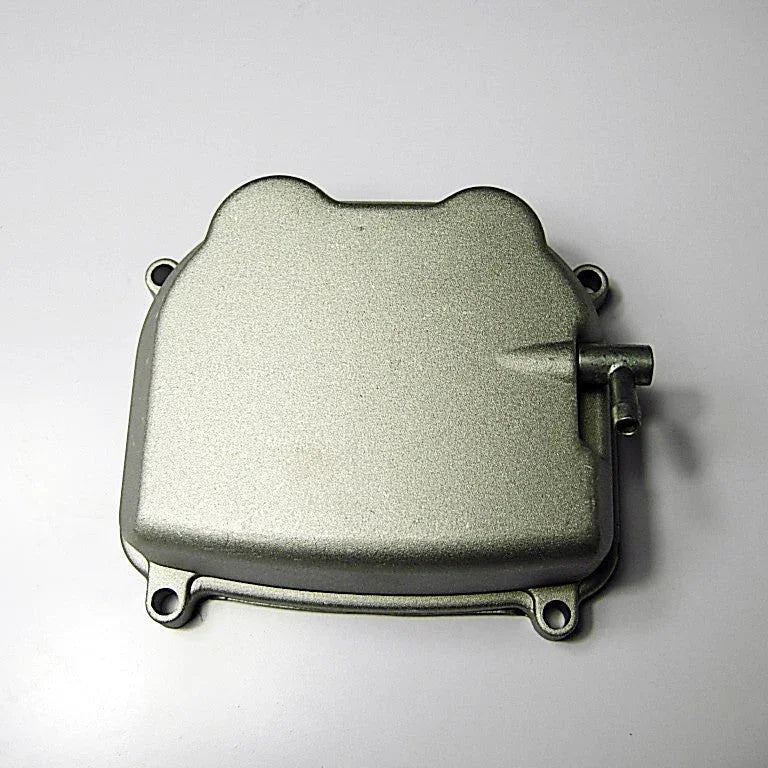 Silver metallic engine cover with mounting holes and a small pipe on a white background