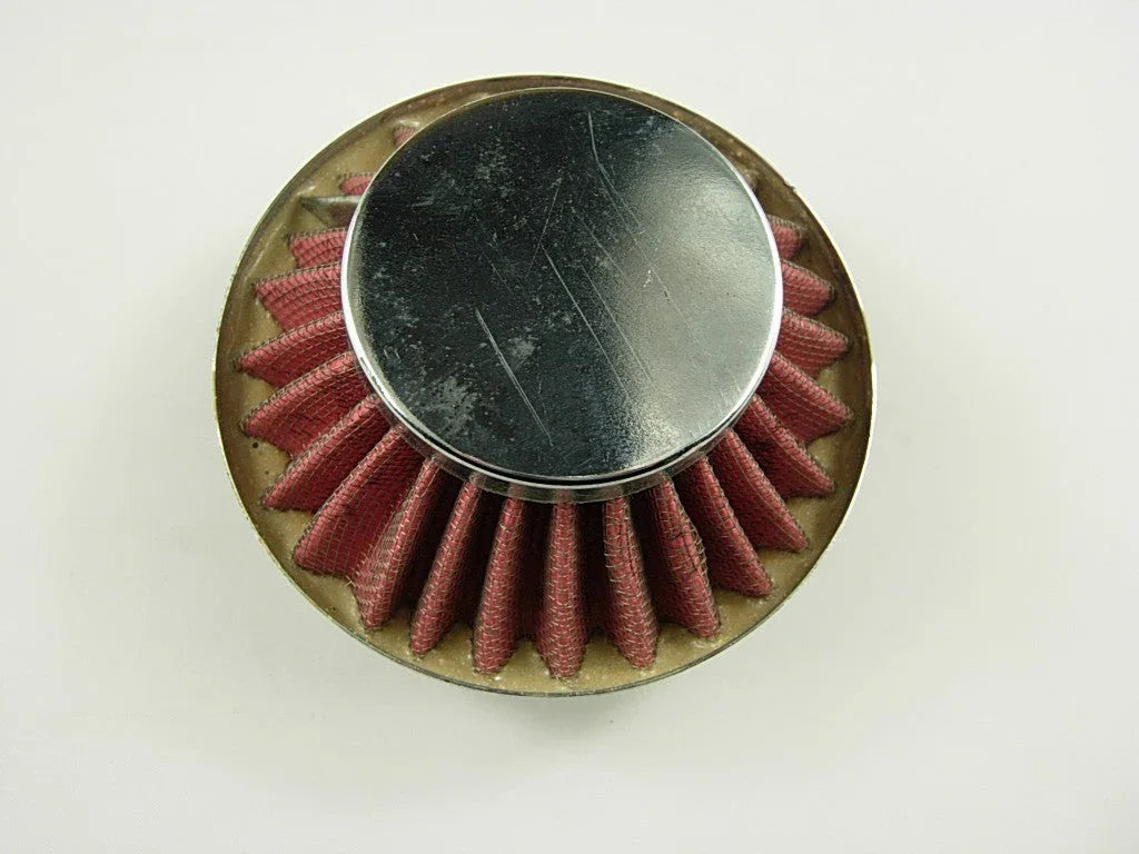 Round red pleated air filter with a shiny metal cap on a white background