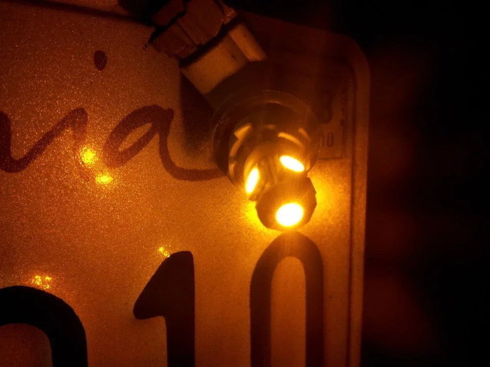 Close-up of an illuminated orange LED light bulb on a reflective surface with black numbers