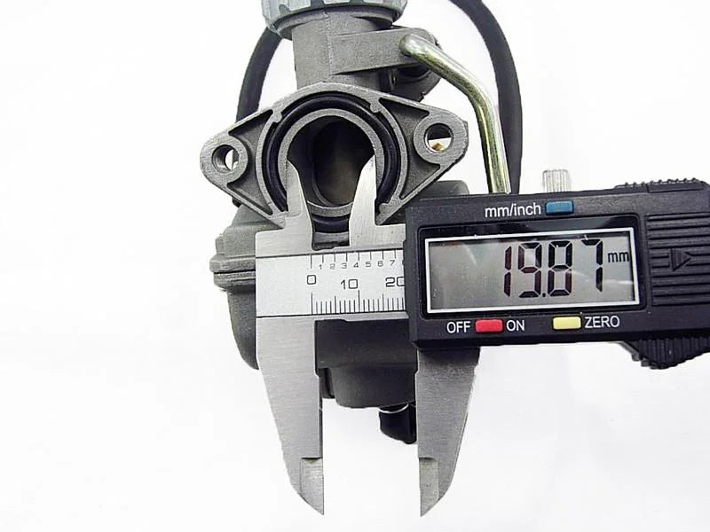 Digital caliper measuring 19.87 mm inside diameter of a metal carburetor part on white background