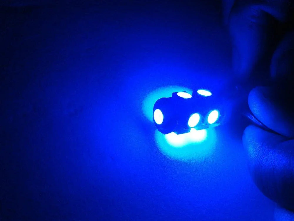 Hand holding small blue LED light emitting bright blue glow on dark surface