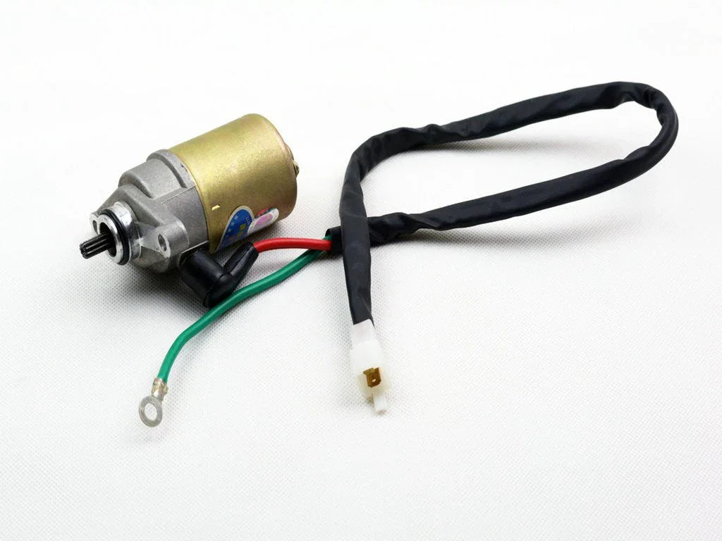 Small electric motor with gold and silver casing, attached black, red, and green wires on white background