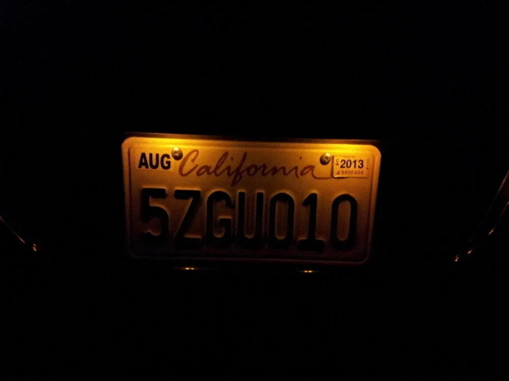 California license plate 5ZGU010 illuminated in dark, with 2013 registration sticker and AUG tag