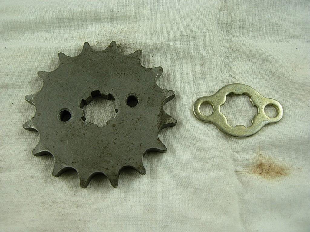 Metal sprocket gear and matching locking plate on white cloth background