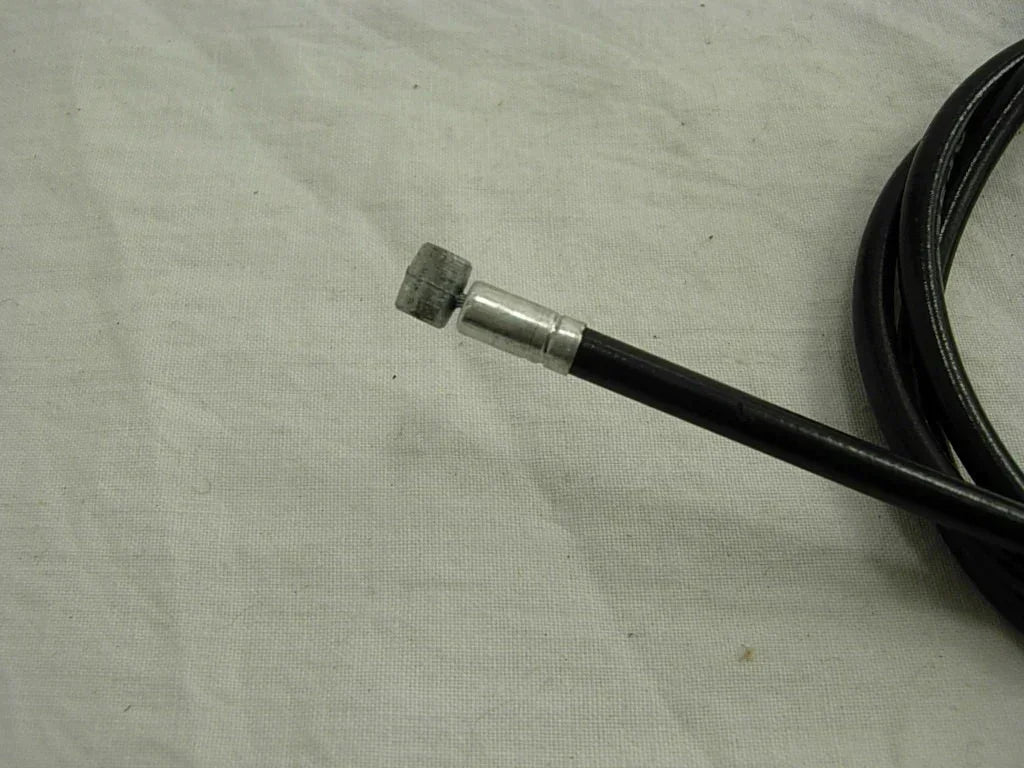 Black motorcycle throttle cable with metal connector, coiled on fabric background