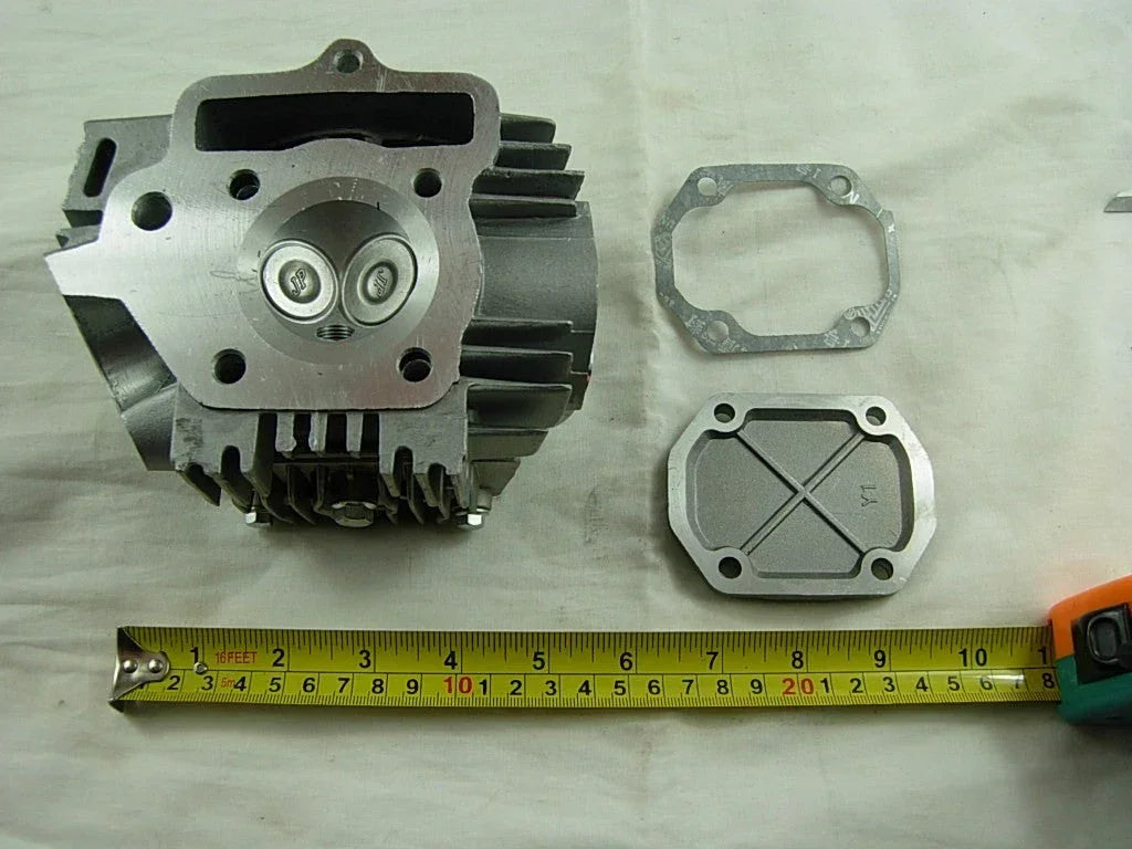 110cc engine cylinder head assembly for dirt bikes by ChinesePartsUSA, showing detailed metal components and mounting points.