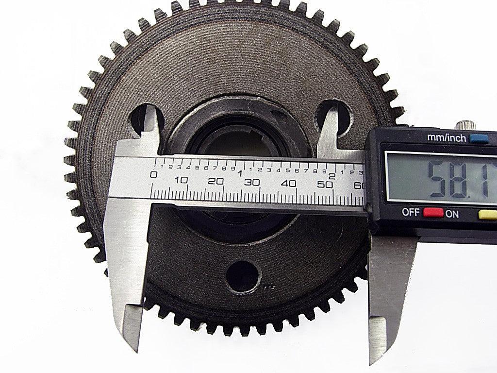 Digital caliper measuring 58.1 mm on a black metal gear with teeth on white background