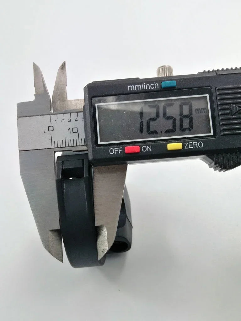 Digital caliper measuring black motorcycle or ATV part at 12.58mm precision