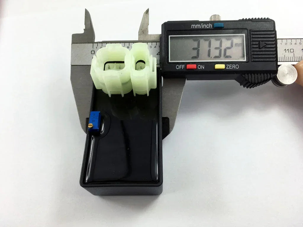 Digital caliper measuring green plastic motorcycle or scooter part, 37.32mm, for engine or electrical assembly