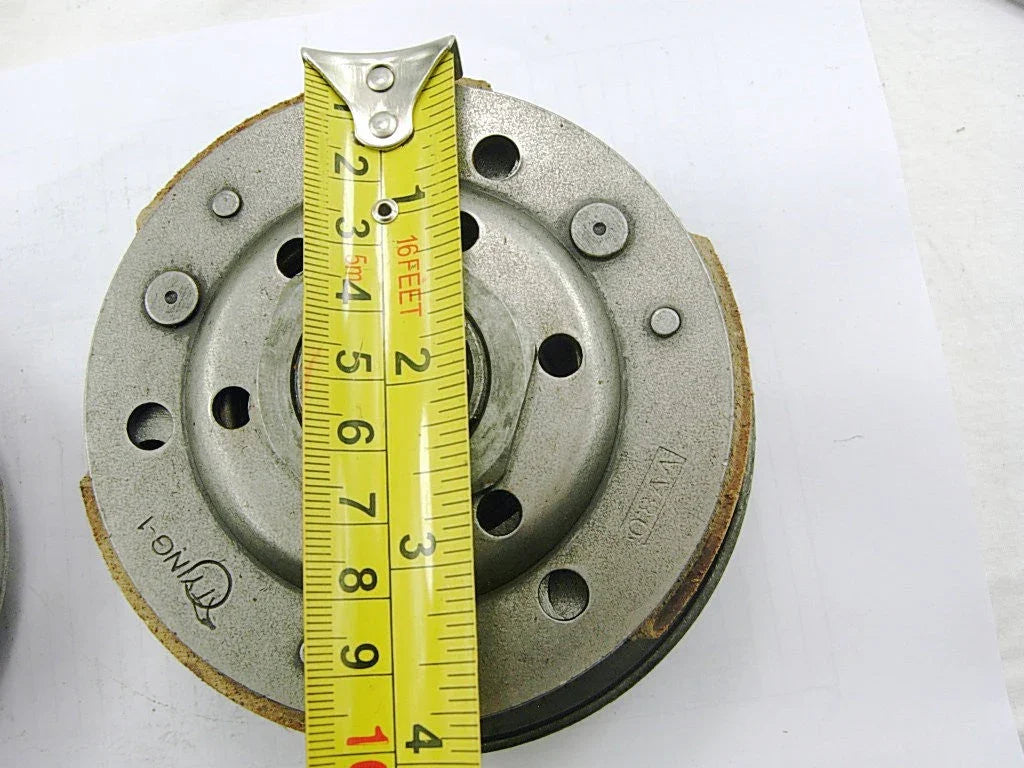 Close-up of a metal clutch plate with a yellow tape measure showing approximately 3.5 inches diameter
