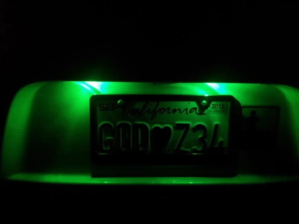 California license plate with custom text GOD♥Z34 illuminated by green light in dark setting