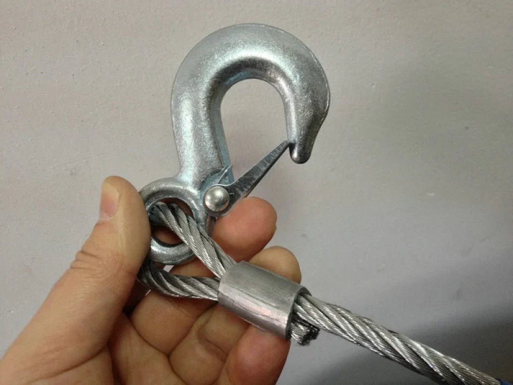Hand holding galvanized steel wire rope with metal safety hook and clamp against gray background