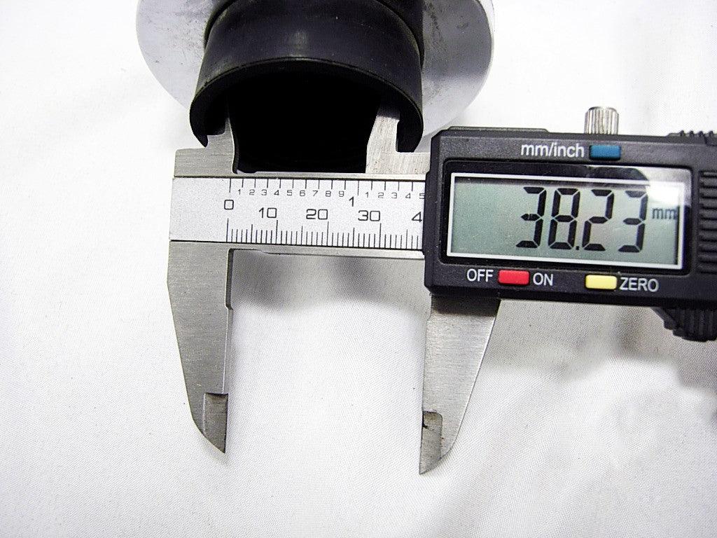 Digital caliper measuring black cylindrical object diameter 38.23 mm on white background