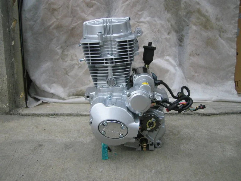 Silver motorcycle engine placed on concrete floor with neutral fabric backdrop