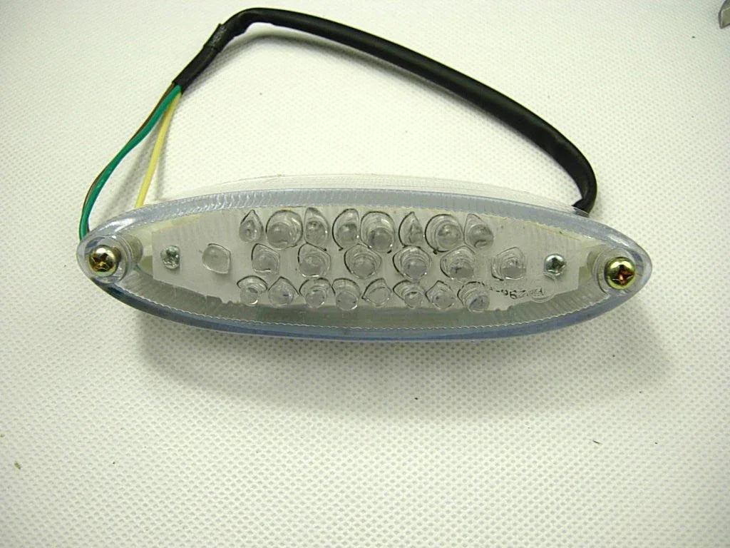 Oval clear plastic LED light with 24 bulbs and attached black cable with green and yellow wires