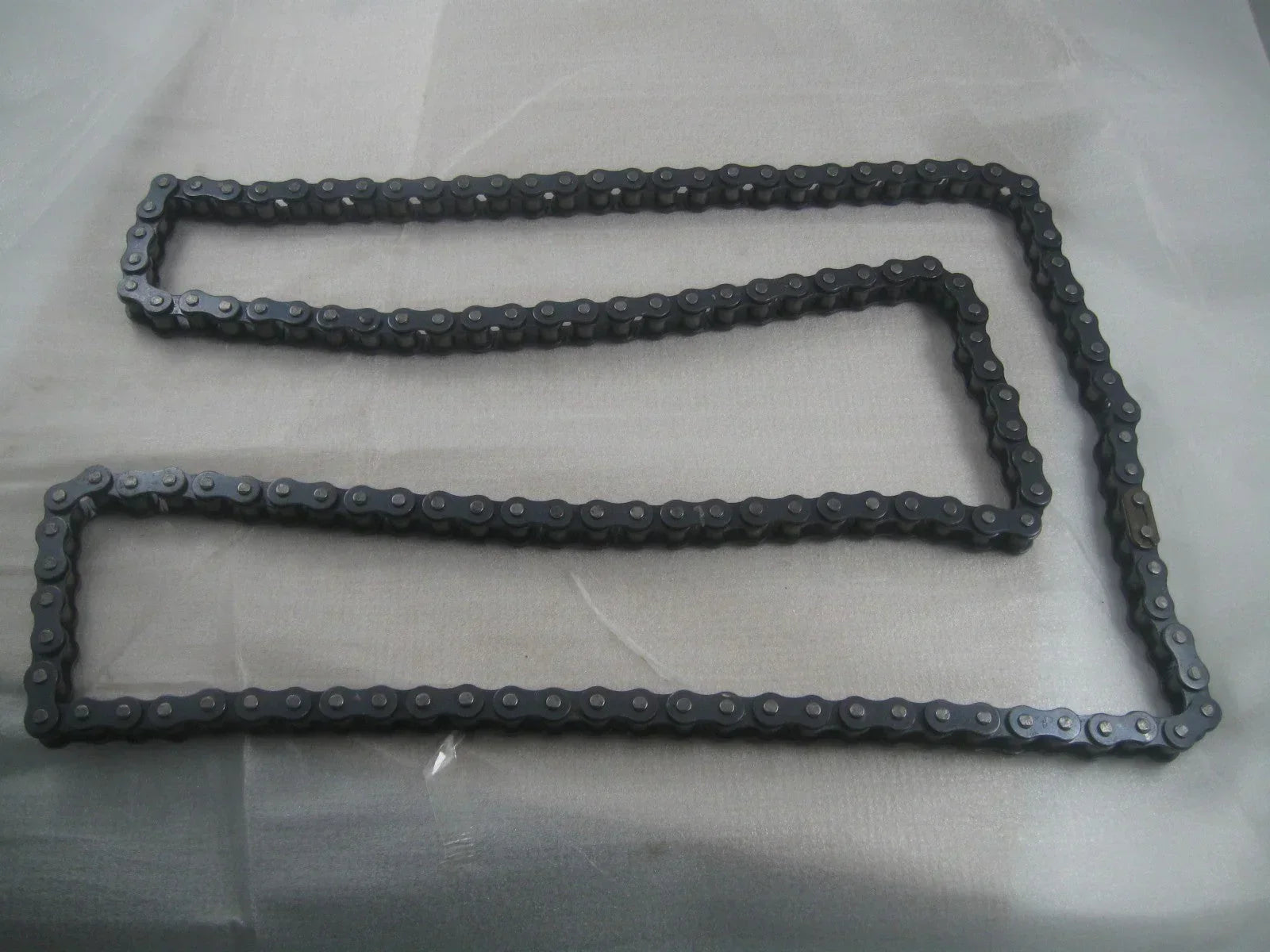 428H dirt bike chain for Apollo and Xmoto, laid flat on a plain surface