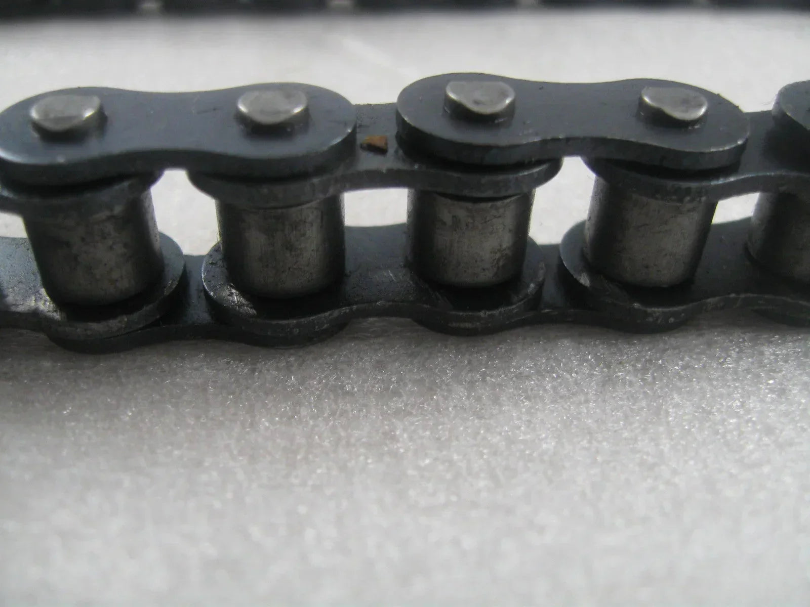 Closeup of 428H dirt bike chain, metal motorcycle part for Apollo XMoto, on white background