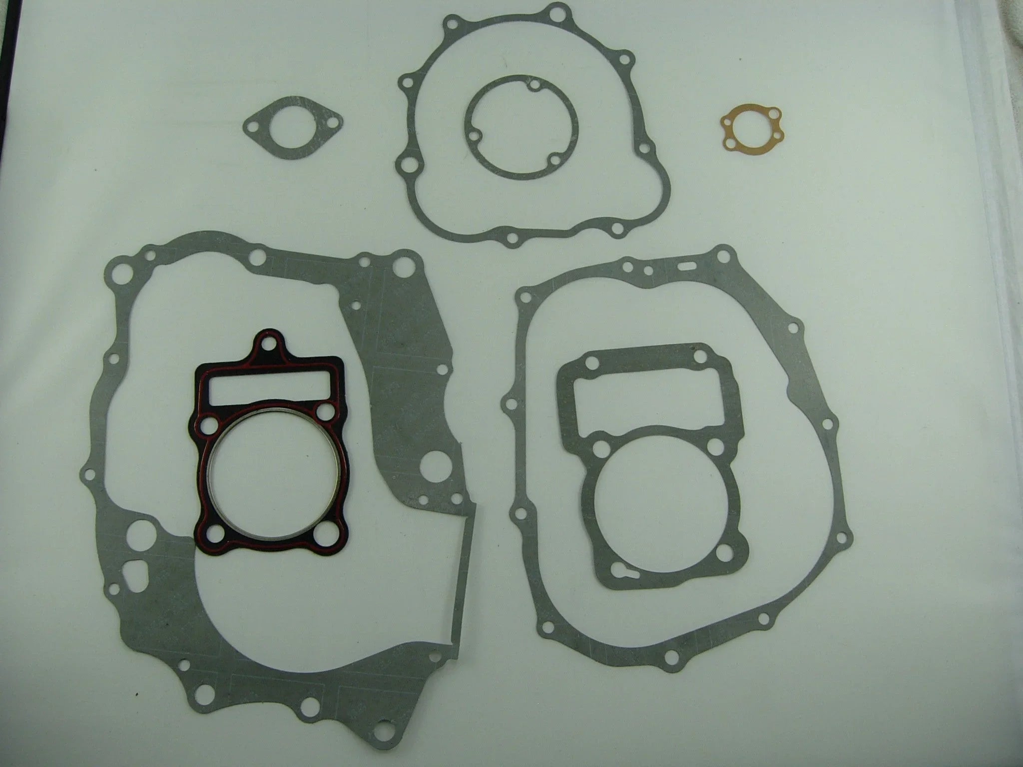 Set of various gray engine gaskets on a white background including large and small shaped gaskets