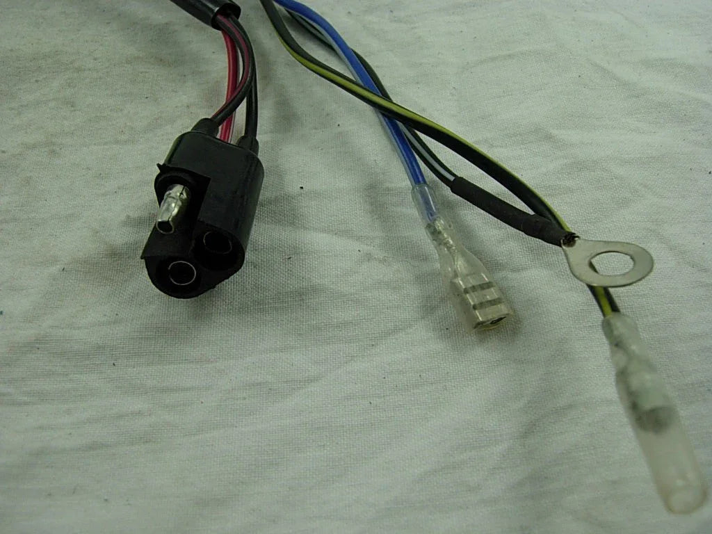 Black electrical connector with attached red and black wires and blue and yellow wiring terminals on white fabric background