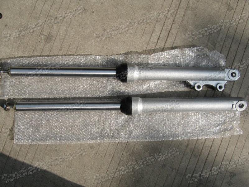 Pair of silver motorcycle front suspension forks on bubble wrap over concrete floor