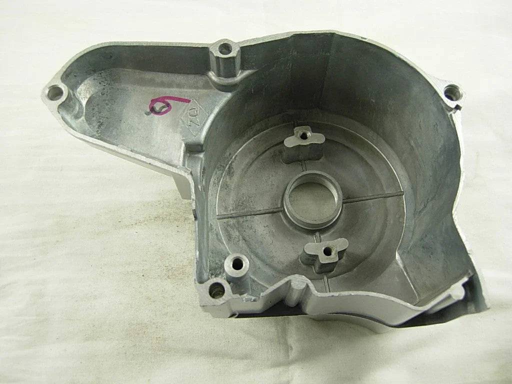 Silver metal engine cover with circular central opening and mounting holes on white background