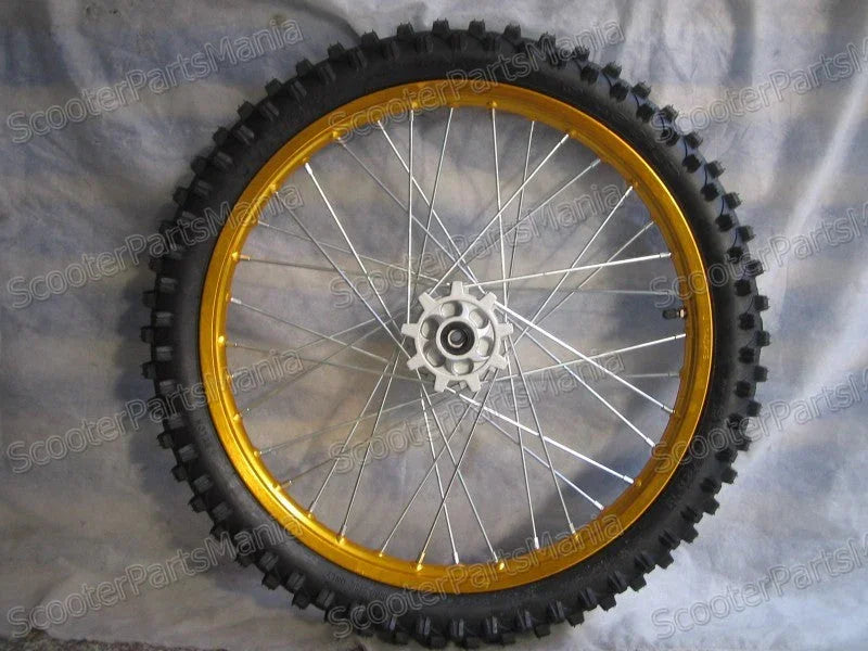 Off-road motorcycle wheel with knobby tire and gold rim on gray fabric background