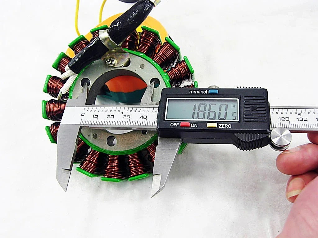 Digital caliper measuring 18.60 mm diameter of copper coil stator on white background
