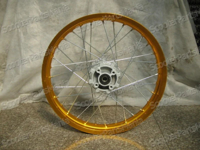 Golden motorcycle or scooter spoked wheel with silver hub and spokes against a fabric backdrop