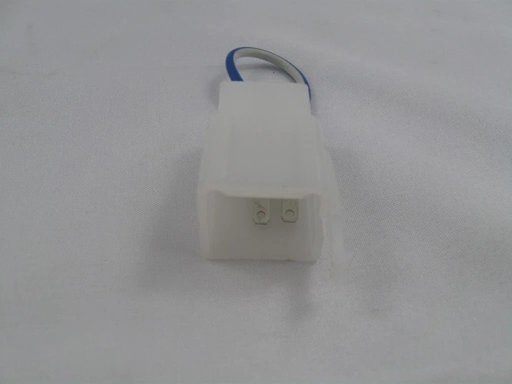 Close-up of white plastic electrical connector with two metal pins and blue wire on white fabric background