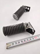 Black ribbed motorcycle suspension spring with metal bracket and measuring tape for size reference