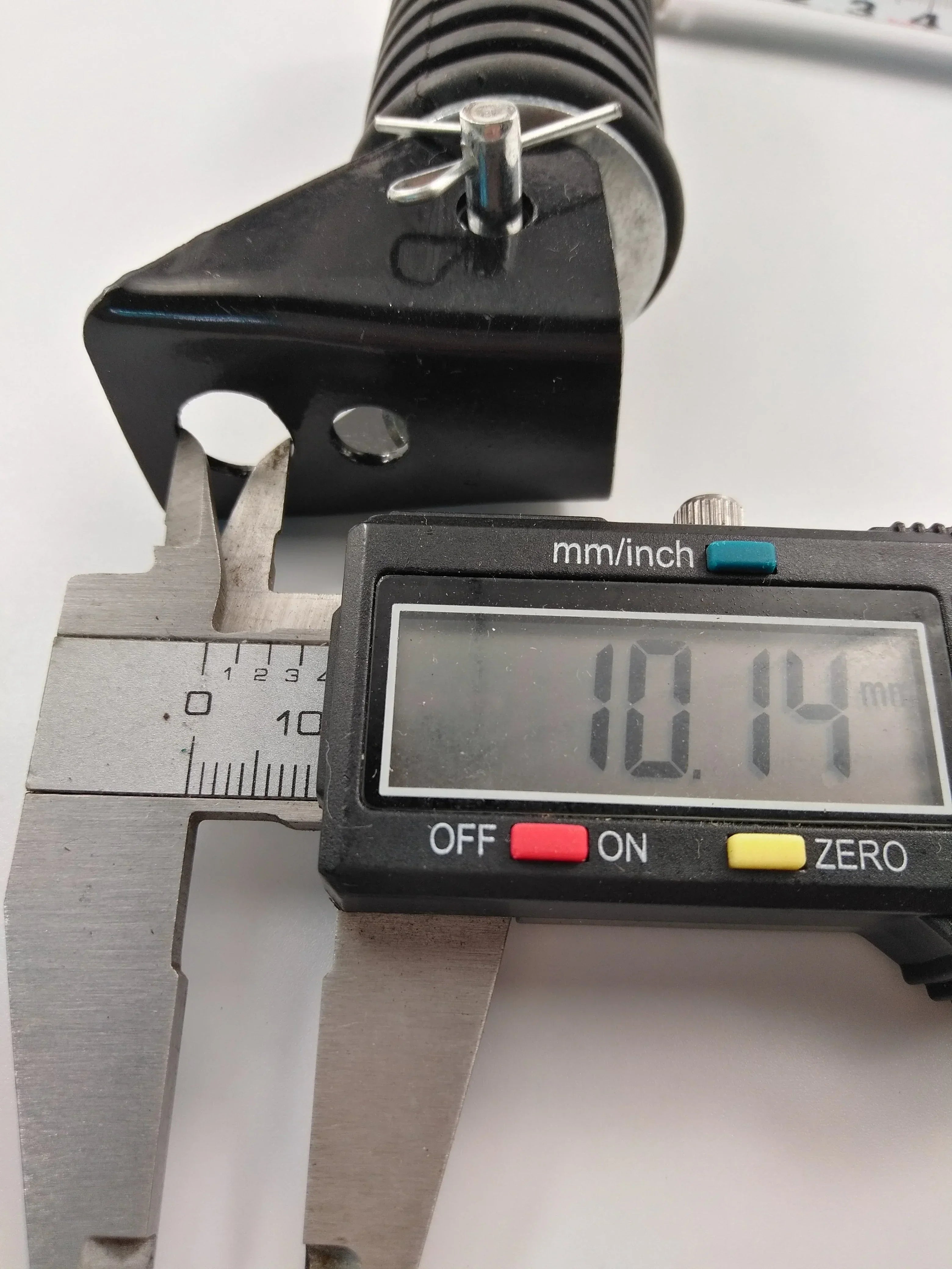Digital caliper measuring black vehicle suspension part at 10.14mm for motorcycle or ATV