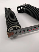 Black coil spring suspension part with mounting bracket, measured with tape for ATV, UTV, dirt bike, or scooter use.