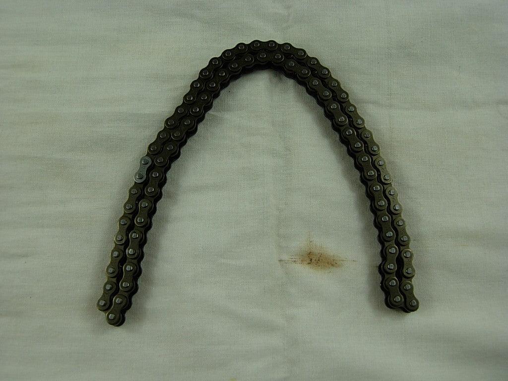 metal bicycle chain arranged in an arch shape on light fabric surface with a small stain