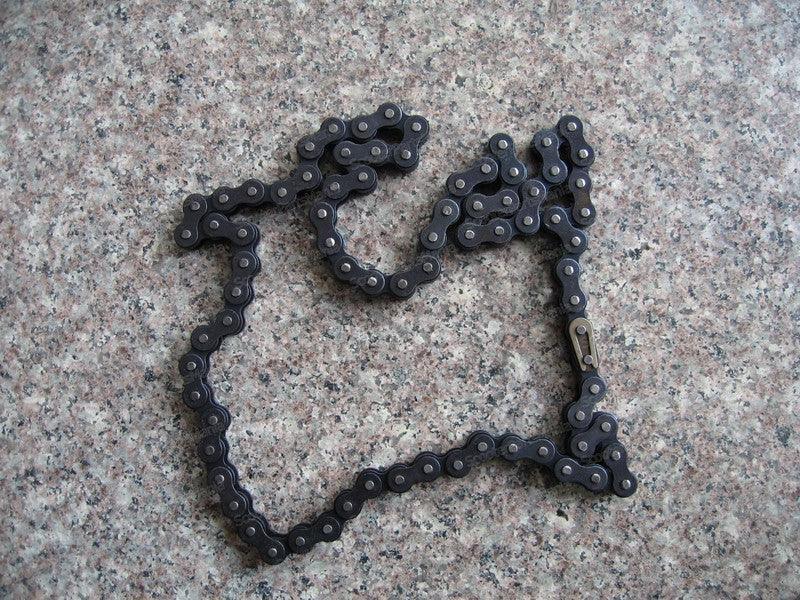420 136-link metal chain for dirt bike or pit bike laid on a granite surface