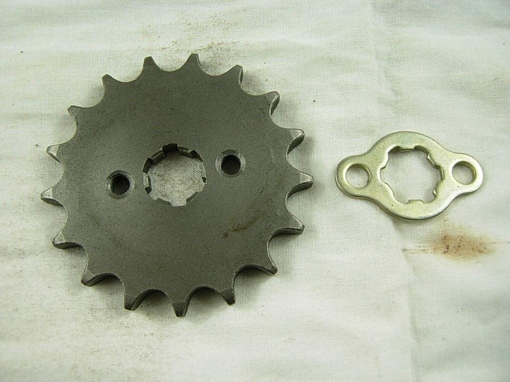 Metal sprocket gear and locking plate on white fabric background