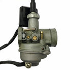 Close-up of a motorcycle carburetor with metal and brass components and attached wiring