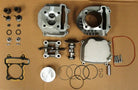 Disassembled motorcycle engine parts laid out on a surface, including piston, cylinder head, cam shaft, gaskets, valves, and bolts