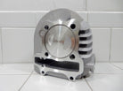 Silver motorcycle engine cylinder with piston marked 63.00 on white tiled surface