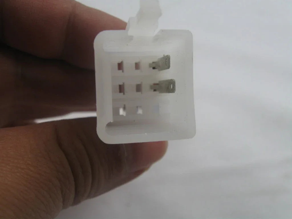 Close-up of hand holding white 6-pin plastic electrical connector on white background
