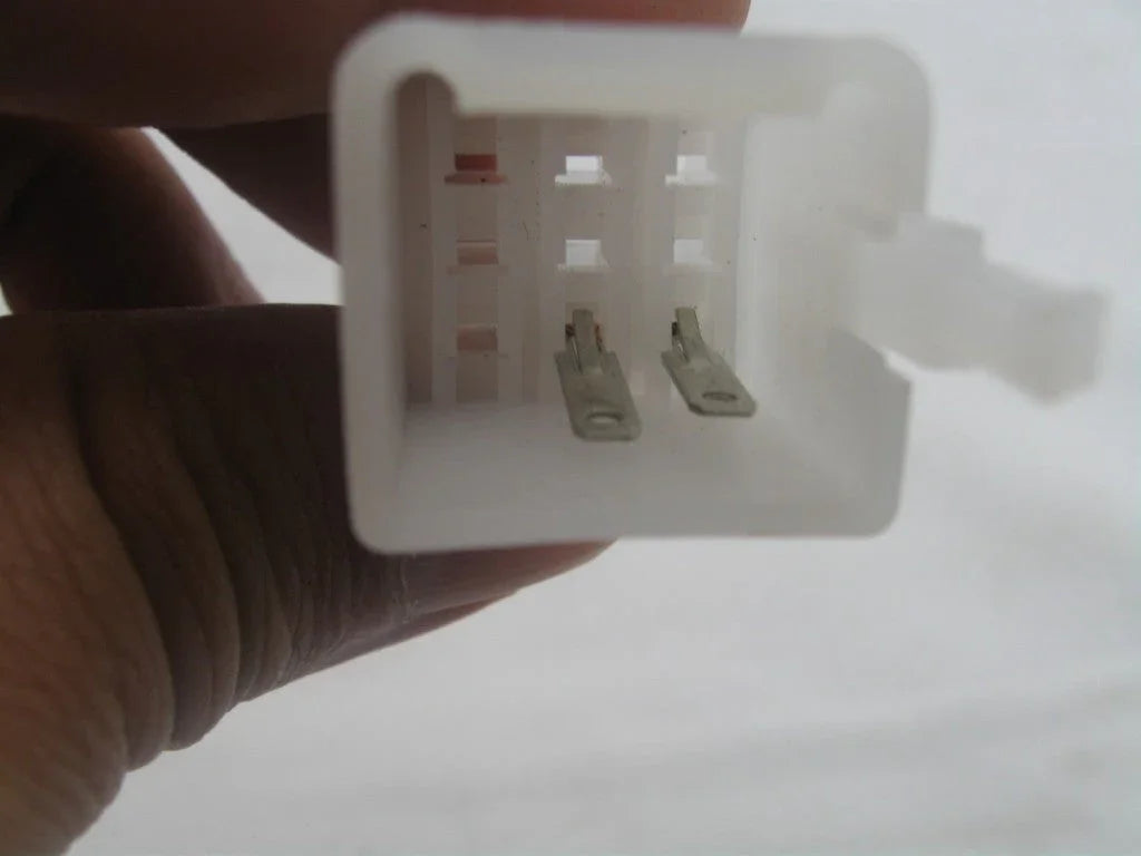 Close-up of hand holding a white rectangular electrical connector with metal pins inside