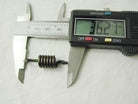 Digital caliper measuring a small black coiled spring, displaying 36.27 mm