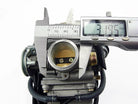 Digital caliper measuring 31.95 mm diameter of a metallic carburetor component on white background