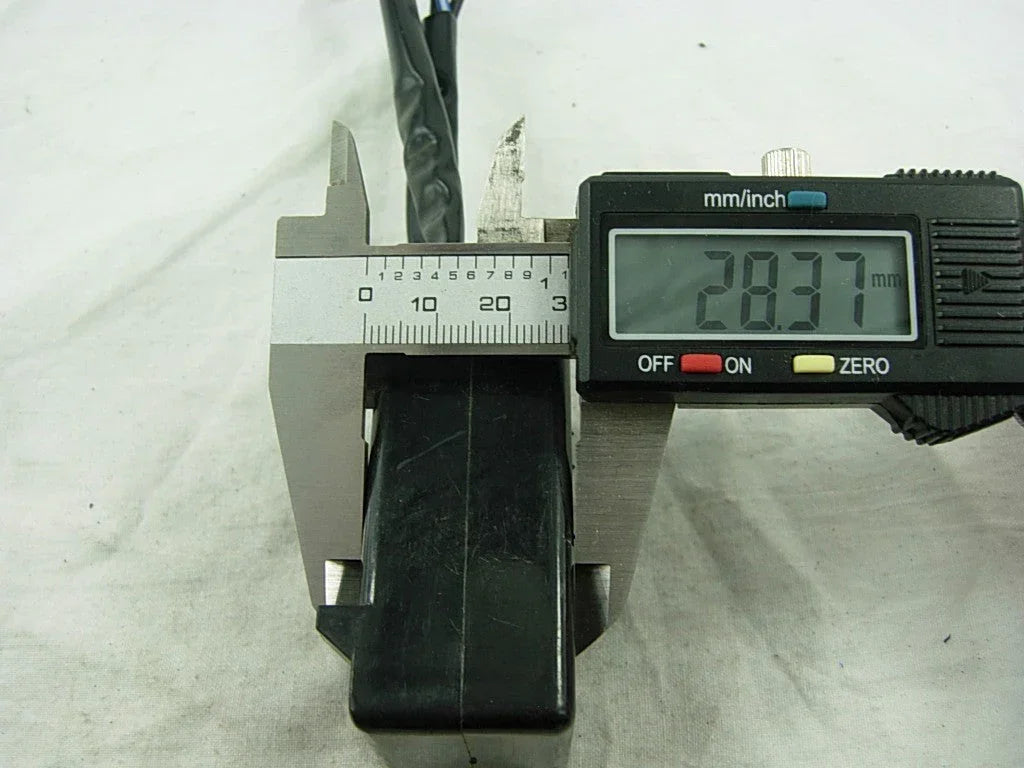 Digital caliper measuring black motorcycle CDI unit at 28.37mm on white background