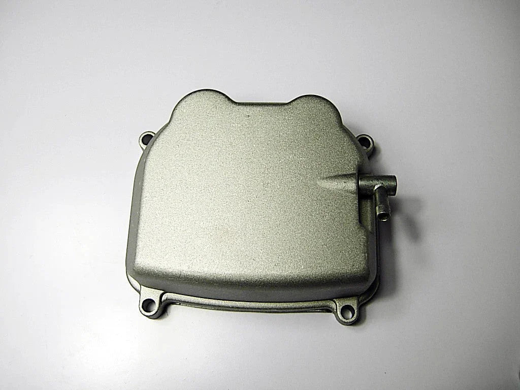 Silver metallic engine cover with mounting holes and a small pipe on a white background
