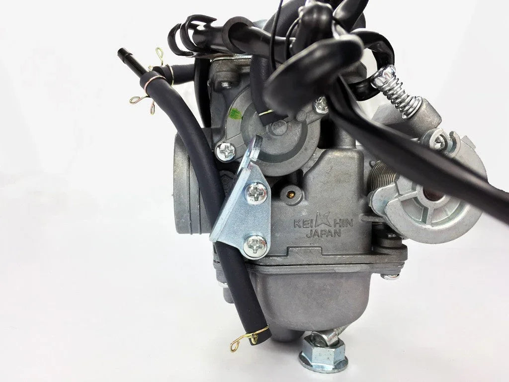 Keihin Japan motorcycle carburetor with attached black hoses and metal fittings on white background
