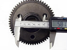 Digital caliper measuring 58.1 mm on a black metal gear with teeth on white background