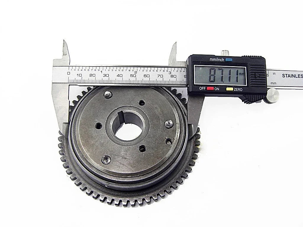 Digital caliper measuring a metal gear with 87.11mm diameter on white background